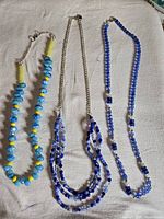Three necklaces laid flat showing designs and clasps