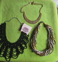 All three necklaces laid out on green background showing overall styles