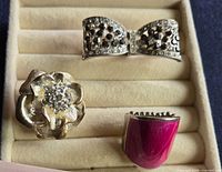 Three rings in tray: bow, flower, enamel shield