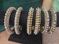 Six gold-tone bangles on display stand