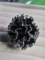 Close-up of black and silver flower ring showing adjustable band and decorative petals