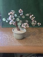 Full view of decorative bonsai tree showing leaves, blossoms and pot