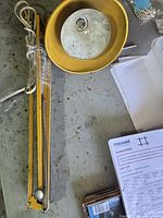 Lamp laid on table showing yellow shade, arm folded, bulb socket visible