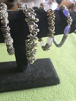Four bracelets displayed on stand: different styles and colours visible