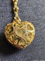 Front view of heart locket showing gold-tone openwork hearts and quartz chips inside