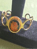 Full view of gold-tone cuff bracelet on display stand
