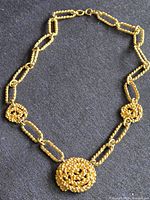 Full view of gold-tone necklace on dark fabric background