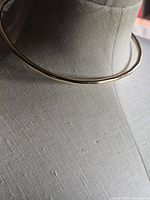 Gold-tone rigid collar necklace displayed on mannequin
