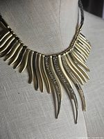 Necklace on form showing curved gold-tone drops with rhinestones