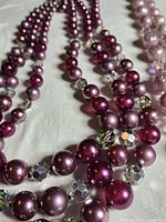 Close view of fuchsia-purple necklace strands with clear faceted spacers