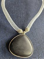 Front view of white mesh necklace and black pendant