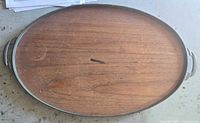 Full view of oval tray top showing wood surface and metal edge