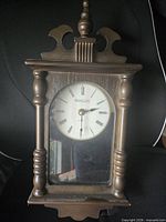Front view of wooden wall clock showing dial and case