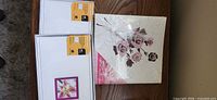 Two sealed Border Trends 4"x6" albums and one sealed Sabre floral album on table