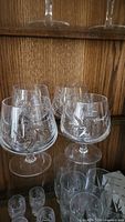 Group of pinwheel cut crystal glasses: brandy snifters, highball tumblers, cordial glasses