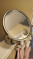 Front view of round chrome vanity mirror showing reflective surface and magnifying spot