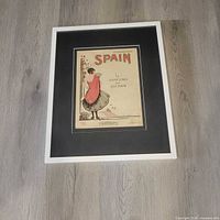 Front view of framed sheet music on floor, shows full frame and mat