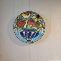 Front view of large round floral ceramic plate mounted on wall