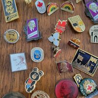 Main group of assorted vintage enamel pins and badges on wooden surface