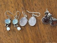 Overview of all three earring pairs on wood surface