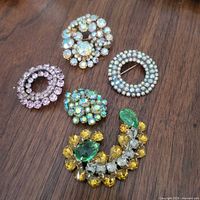 Group view of four rhinestone brooches on wood surface