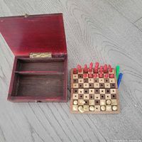 Open wooden box and separate peg chess board with some pieces set up