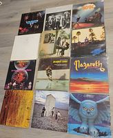 Overview of 12 vinyl record covers laid out in three-by-four grid on floor