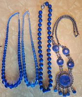 All four blue necklaces laid out side by side