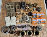 All items laid out showing variety of brass switch plates, door hardware, latches, lamp parts