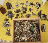 Overview of wooden tray filled with hundreds of assorted keys and surrounding bundles and padlocks