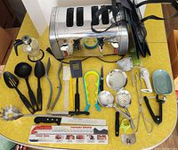 overview of all items on table including toaster, utensils, knives, bags