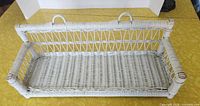 Front view of white wicker wall shelf showing overall structure and hanging loops