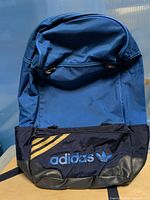 Front view of Adidas backpack showing color, logo, stripes, pocket