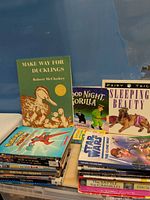 Overview showing Make Way for Ducklings, Good Night Gorilla, Sleeping Beauty and stack of additional books