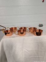 All six copper cups displayed on cloth