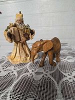 Front view of Santa figurine and wood elephant on lace surface