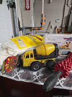 Lot overview with toy cement mixer, bag of rags, cooling mat box, massage roller
