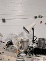 Telephone, desk lamp, metal tankard, cords visible
