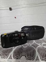 Front view of Minolta Freedom Action Zoom camera with case beside