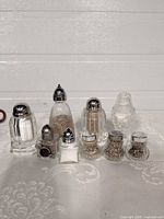 Group of ten assorted clear glass salt and pepper shakers with metal or plastic caps