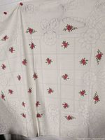 Full view of rectangular ivory tablecloth hanging, showing rose motif layout