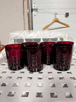 Front view of six dark red geometric cut tumblers