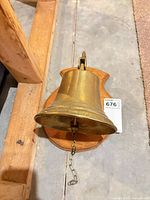 Front angled view of brass ship bell on wood plaque showing overall design