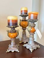 Front view of three ornate candlesticks with candles