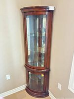 Front view of dark wood corner curio cabinet showing glass doors and shelves
