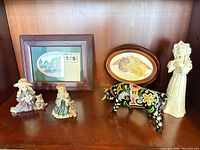 Shelf with framed print, pressed flower art, two girl figurines, ceramic bull, tall white figurine