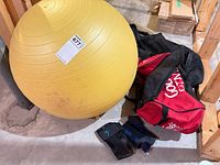 Yellow exercise ball, red GoodLife bag, wrist braces on floor