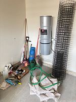 Wide view of entire lot including long-handled tools, hose, fencing roll and hand tools on board