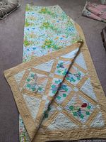 Quilt laid out showing front patchwork design and partial view of floral reverse