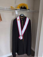 Full view of cape on hanger with sash and hat on shelf